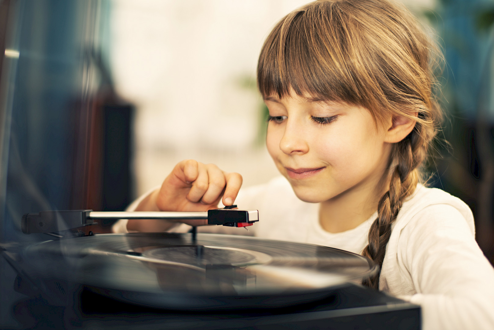 A young girl places the stylus on a vinyl record